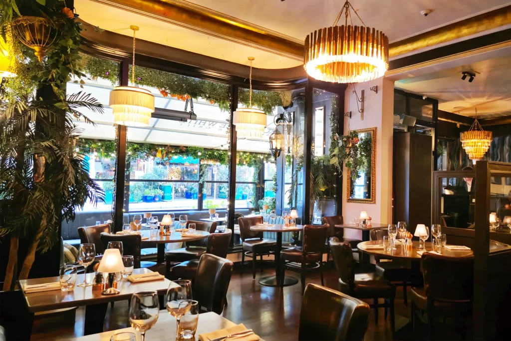 The elegant interior of Marco Pierre White Steakhouse & Grill Dawson Street features warm lighting, lush greenery, and stylishly set tables, creating a cosy and luxurious fine dining atmosphere in Dublin.