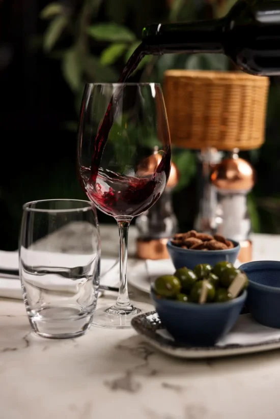 Red wine being poured into glass with olives and almonds on marble table at Marco Pierre White Steakhouse & Grill Dublin 2