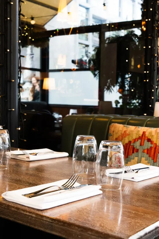 Set dining table with glassware, cutlery and kilim cushion banquette at Marco Pierre White Steakhouse & Grill Dublin 2
