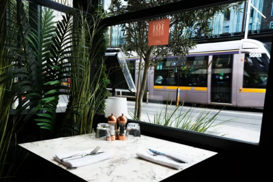 Window table for two with Dawson Luas tram passing outside at Marco Pierre White Steakhouse & Grill Dublin 2