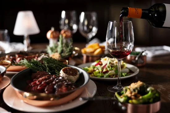 Red wine being poured with Côte de Boeuf and sharing sides at Marco Pierre White Steakhouse & Grill Dublin 2
